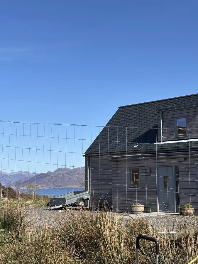 The couple's dark timber self-build house with the Sound of Sleat and mainland hills behind it.